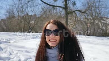 戴着深色太阳镜的美丽成年女孩的冬季肖像，享受阳光明媚的一天，等待春天的时光